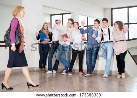Teacher walking by a group of students in school hall