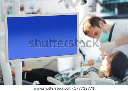 Young teenage girl at modern dentist\'s office with large screen for copy space