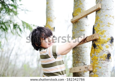 Happy kid having fun climbing on ladder in forest cabin