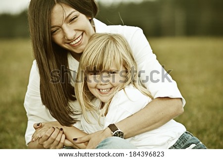 Colorized photo of am other and her little girl on green summer grass meadow having fun