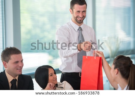 Smiling business man handing gift to female colleague