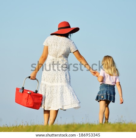 Mother and daughter walking together on beautiful summer meadow enjoying and having fun
