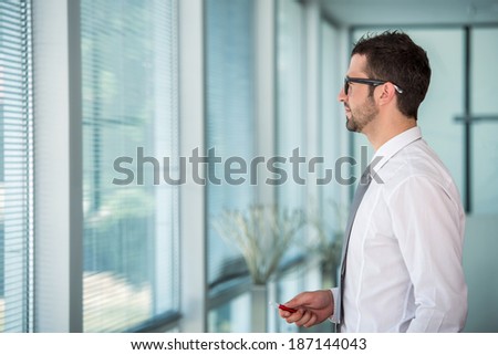Handsome business man looking through office window