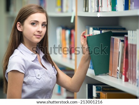 College student on university campus picking book from shelf