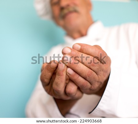 Elderly chef in white cook uniform holding food in hands