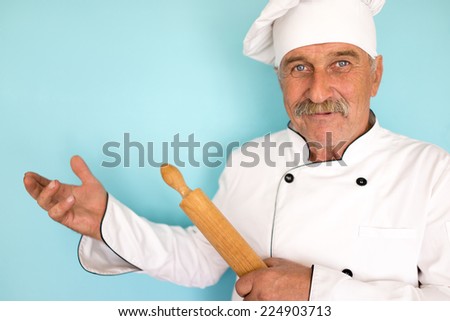 Elderly chef in white cook uniform using rolling pin