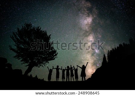 Happy kids group silhouette with Milky Way and beautiful night sky full of stars in background