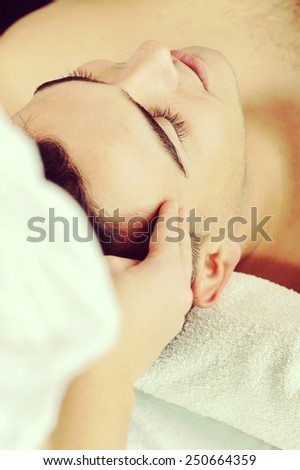 Side view of young man receiving head massage at health spa