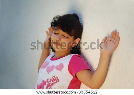Adorable girl putting her hands and head on wall