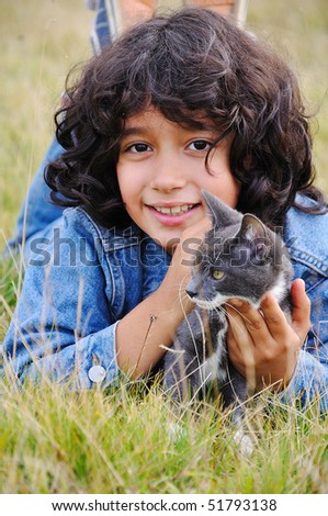 Very cute little girl with cat on meadow