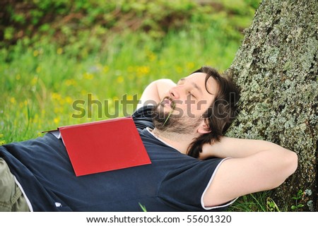 Education in nature, sleepy man under the tree with the book on his chest