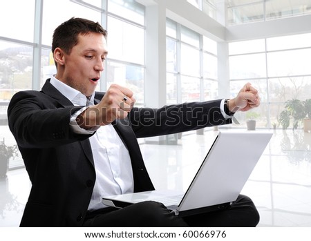 successful man with laptop in modern white office with glass around