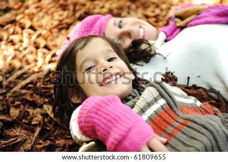 Happy family, mother and son, woman and child on autumn orange leaves. Outdoor.