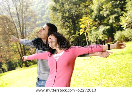Two young relaxed people in nature with opened arms looking up and breathing fresh air