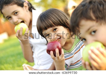 Small group of children eating apples together, shallow DOF