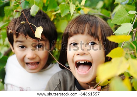 Happy childhood outdoor, happy faces between the leaves of the trees in forest or park, look for more in my porftolio
