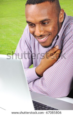 Young man, african american smiling man with a laptop in nature, outdoor, student or young businessman