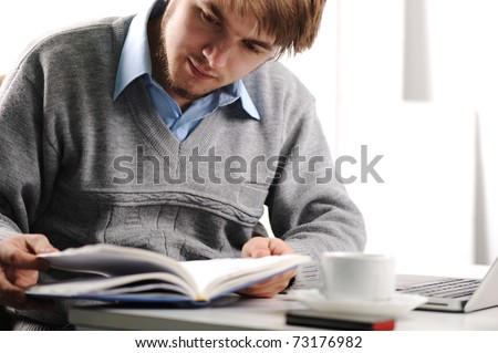 Young blond man reading a book on the desk