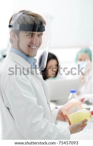Team working with microscopes in a laboratory, young male scientist with mask smiling while experimenting