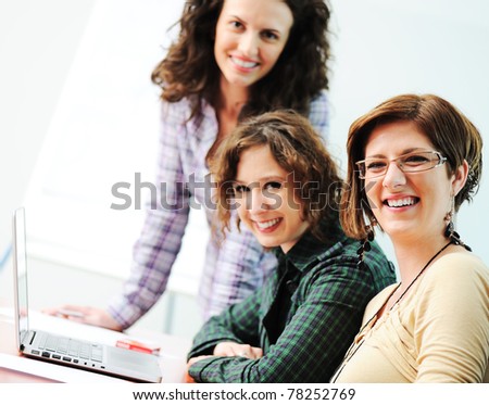 Group of young happy people looking into laptop working on it