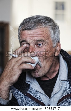 Old man with mustache smoking cigarette and drinking coffee
