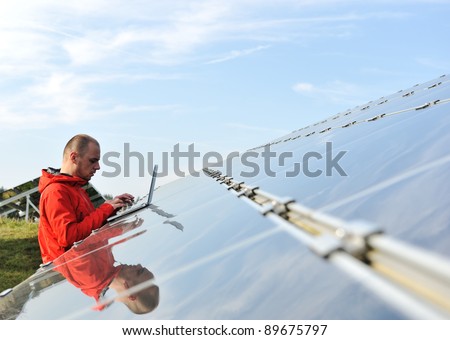 Male engineer at work place, solar panels in background