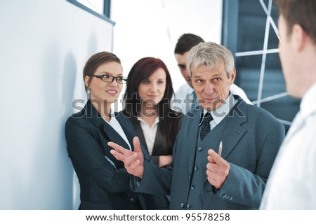 Small business team in the office in front of a whiteboard discussing a project
