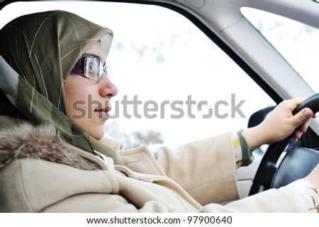 Arabic Muslim woman driving car wearing traditional scarf