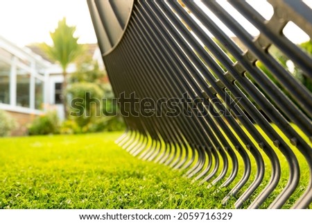 Ground level view of a typical garden rake seen being used after a mow on a healthy lawn. The rake is being used to clear up debris and garden leaves. Stock fotó © 