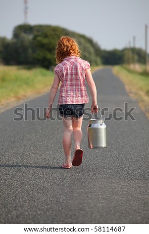 Red-haired girl with milk can on her way to the farm