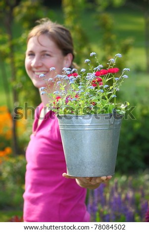 A young gardening woman enjoys a sunny day in the garden
