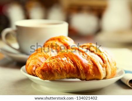 breakfast with croissants, cup of black coffee  and newspaper