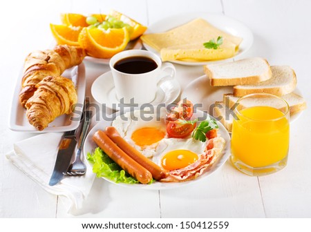 breakfast with fried eggs, croissants, juice, coffee and fruits