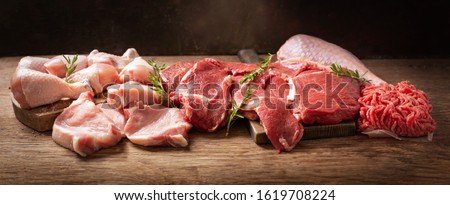 various types of fresh meat: pork, beef, turkey and chicken on a wooden table