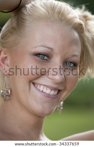 Close up of a beautiful young smiling blue-eyed blonde Caucasian woman in outdoor setting