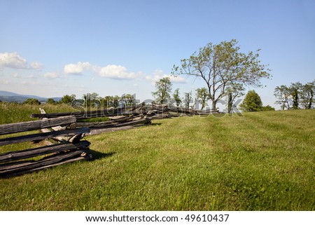 Beautiful mountain meadow with split rail fence, trees and blue skies
