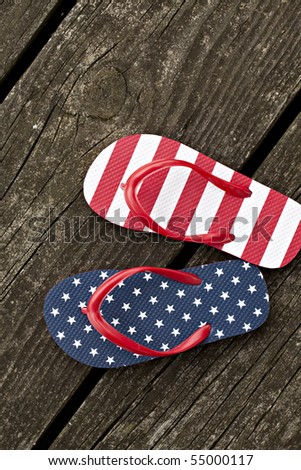 Beautiful flip flops, one with stars and the other with stripes, sitting outdoors on old weathered wooden pier that has moss and lichens on it.