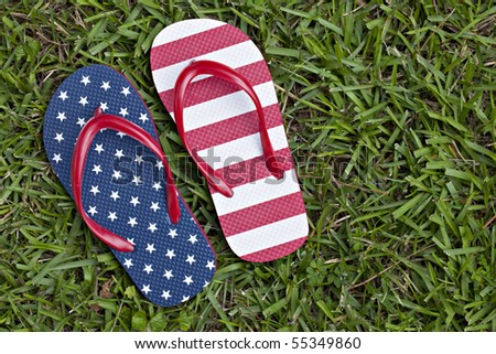 Beautiful flip flops, one with stars and the other with stripes, sitting outdoors in grass