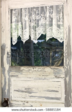 Beautiful old wooden door with peeling white paint and lacy curtains