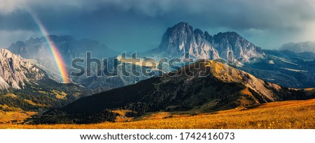 Fantastic dramatic view on Dolomites Alps. Italy. Wonderful nature landscape. Scenic image of Mountain valley with majestic mountains, overcast sky and rainbow during sunset. great natural background