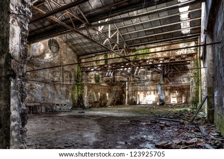 interior of abandoned factory with rubble and debris - desolate room of an old destroyed industrial warehouse - hdr image