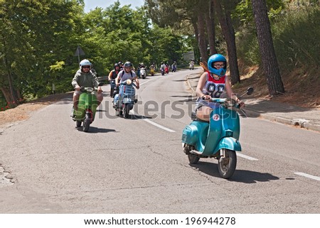 MONTIANO, FC, ITALY - MAY 25: unidentified girl leads a group of bikers riding a vintage italian scooter Vespa at motorcycle rally \