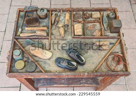 work table with small shoes for children and old tools of the artisan shoemaker for repair and finishing shoe