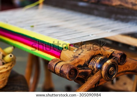 A closeup image of an old weaving Loom and thread of yarn.