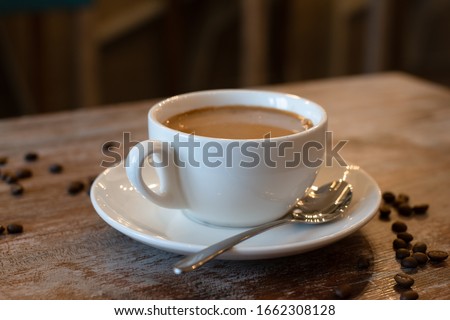 A white cappuccino mug stands on a wooden table. Coffee grains are spread on the table ストックフォト © 