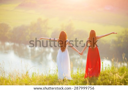 Two young women enjoying nature. Free Happy Women. Lit evening sun. Freedom concept. Lesbian couple.
