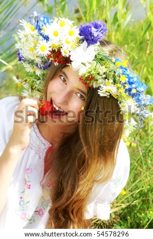 Portrait of a beautiful girl with flower diadem  eating strawberry