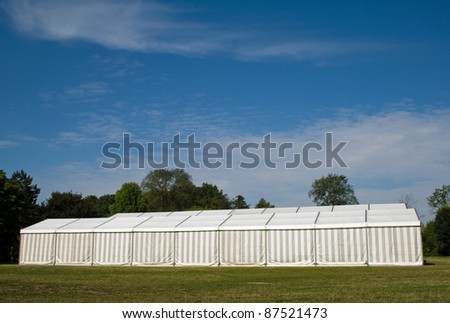 A white party or event tent on a meadow in a public park