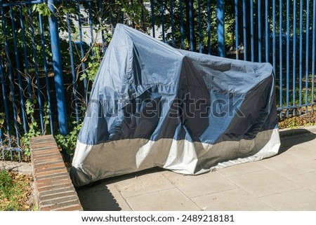 Similar – Image, Stock Photo Waterproof cover for motorcycle with silver reflective protective surface. Motorcycle covered with fabric shield and parked outside