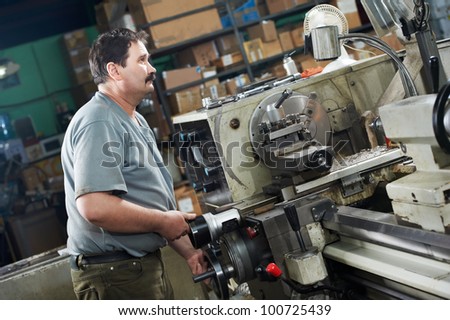 mechanical technician worker at metal machining lathe in tool workshop